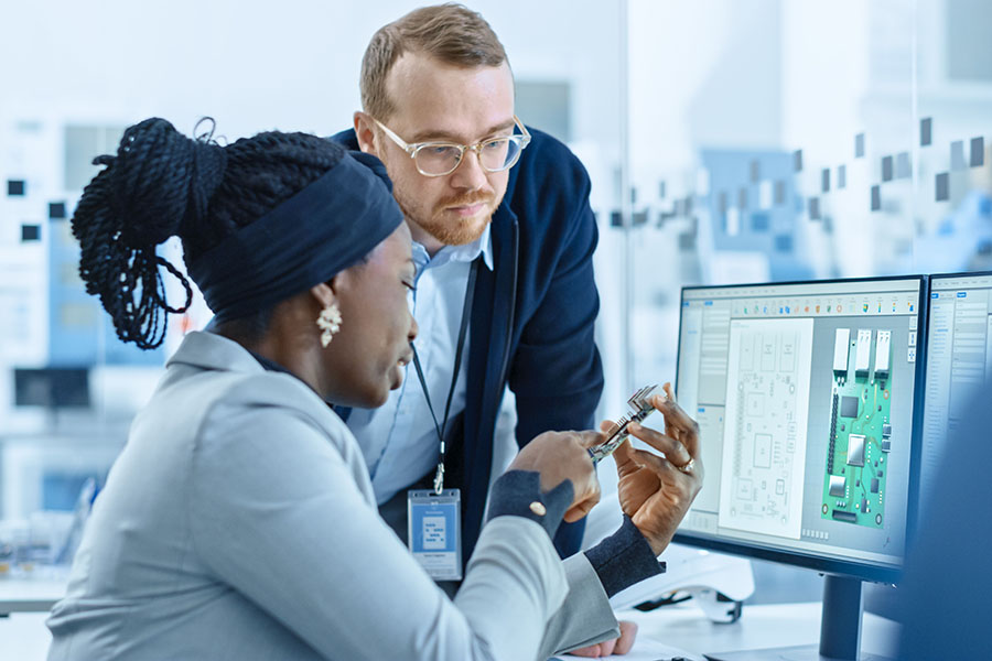 stock image of woman working on circuit design with man at computer