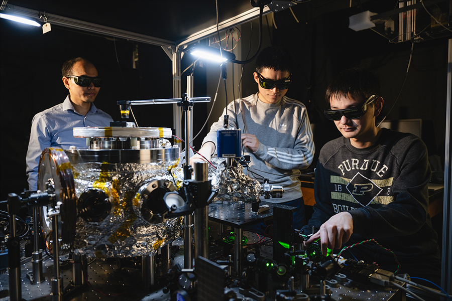 Three men in a laboratory setting, utilizing machines and equipment for their research and experiments