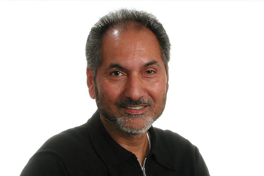 A bearded man wearing a black shirt, looking confidently at the camera with a neutral background.