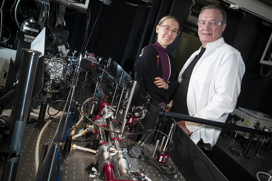 A woman and man standing in a lab next to equipment and looking at the camera
