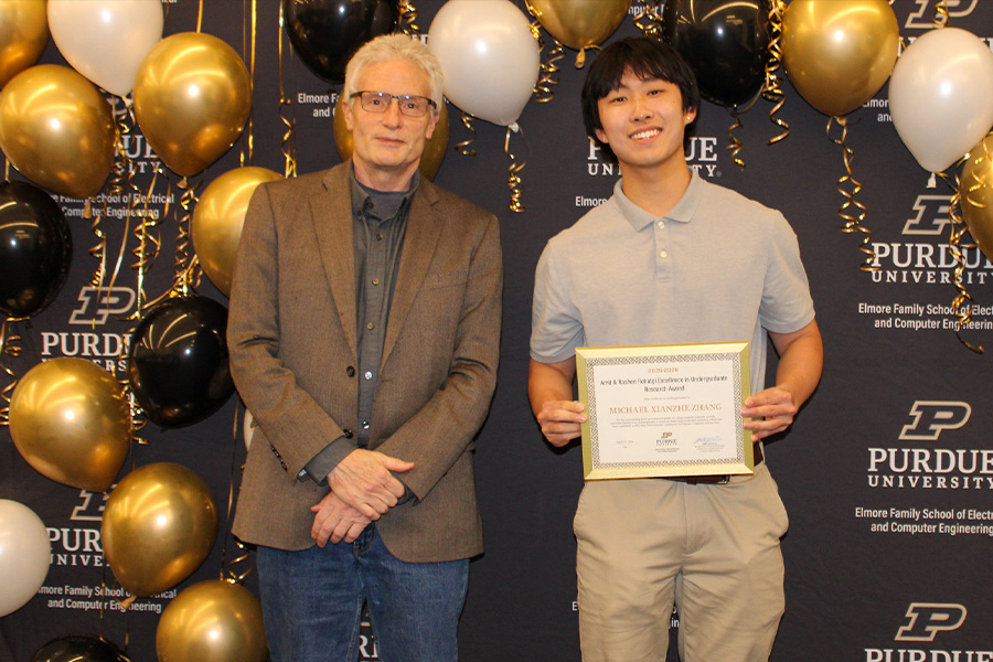 Purdue University Electrical and Computer Engineering awards ceremony photo featuring Michael Xiangjie Zhang holding an undergraduate research award certificate beside a faculty member, with a black Purdue University backdrop and gold, black, and white balloons.