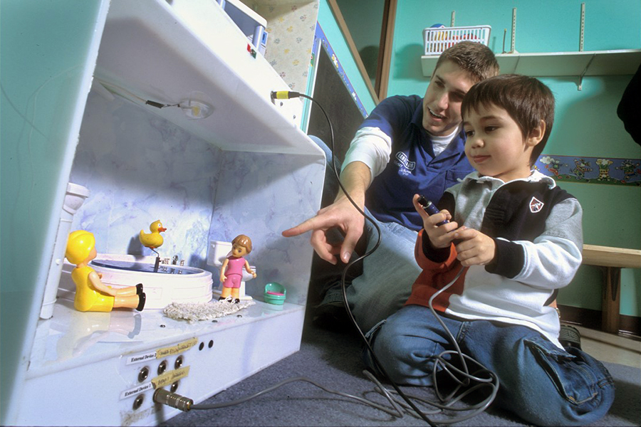 Young person with college student using EPICS project dollhouse