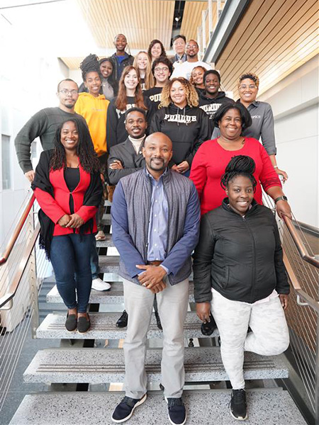 Group of people, some wearing Purdue sweatshirts, standing on stairs