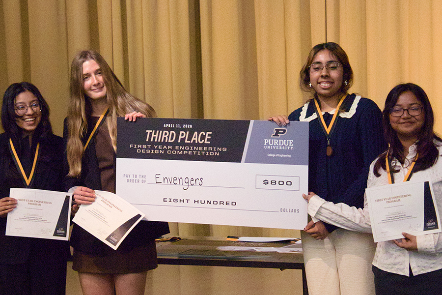 Students smiling holding a big check