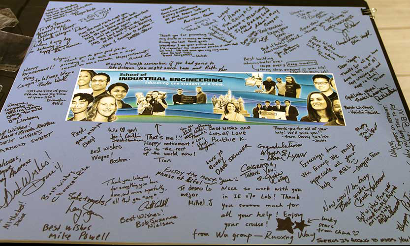 Well-wishers' signatures on a replica of the Grissom Hall Photo Wall featuring Wayne with students.