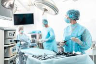 Medical team preparing for sterile surgery, medical worker holds endoscopy device and looks at screen