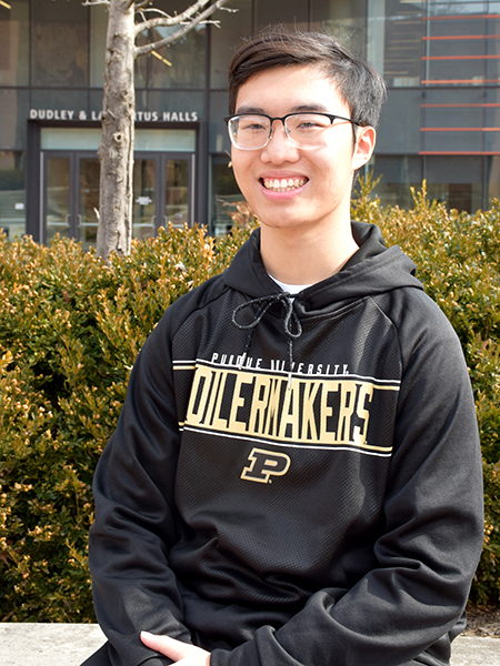 Calvin Hoang smiling, wearing glasses and black sweatshirt with "Purdue"