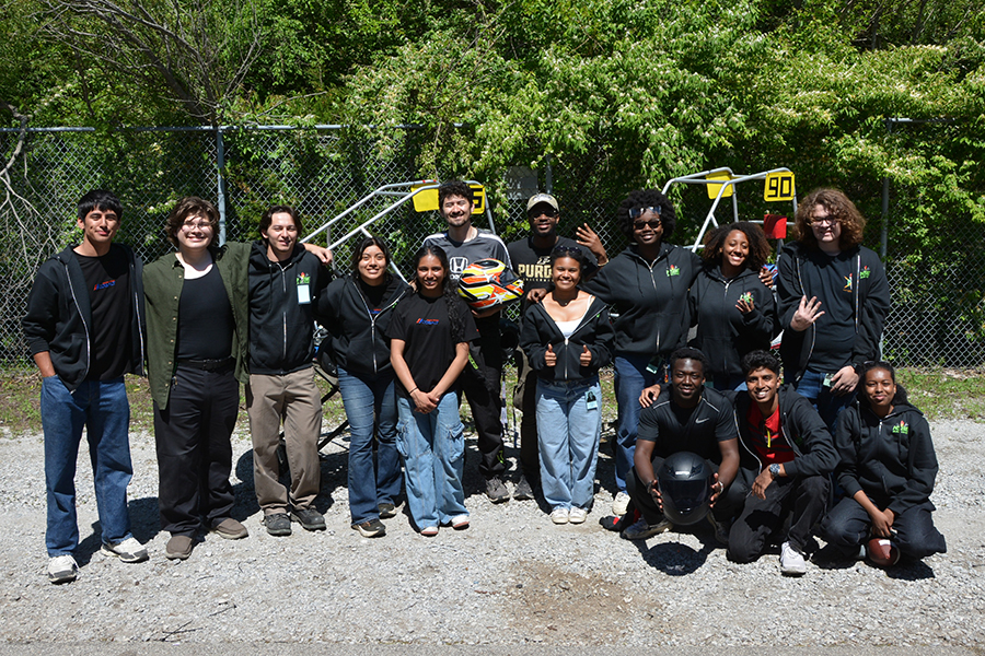 A group of students, standing near a go-kart on the Grand Prix track