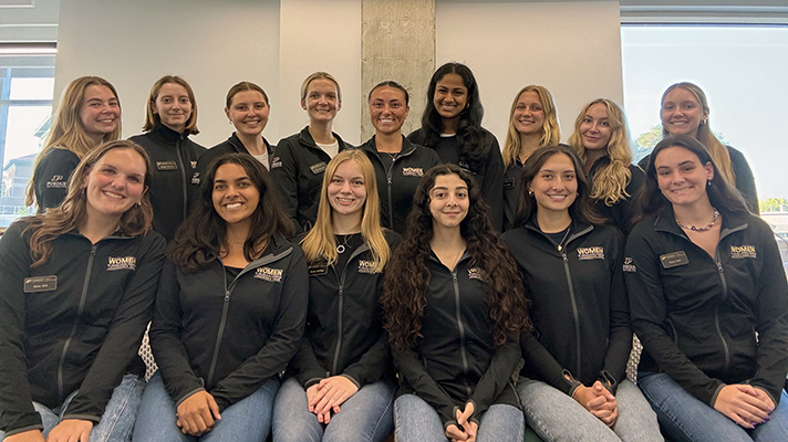 Group of students wearing matching black zip-up fleeces with "Women in Engineering Program" co-brand on sleeve