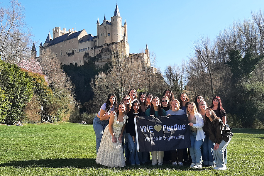 Student standing in front of a castle, holding Purdue flag